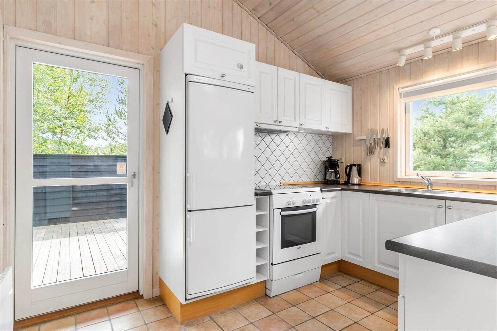 Kitchen with white cabinets, refrigerator, and view of the terrace.
