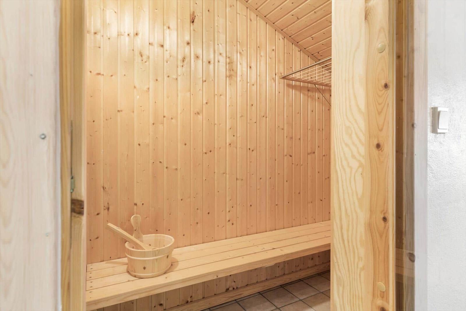 Sauna with wooden walls, bench, and wooden bucket.