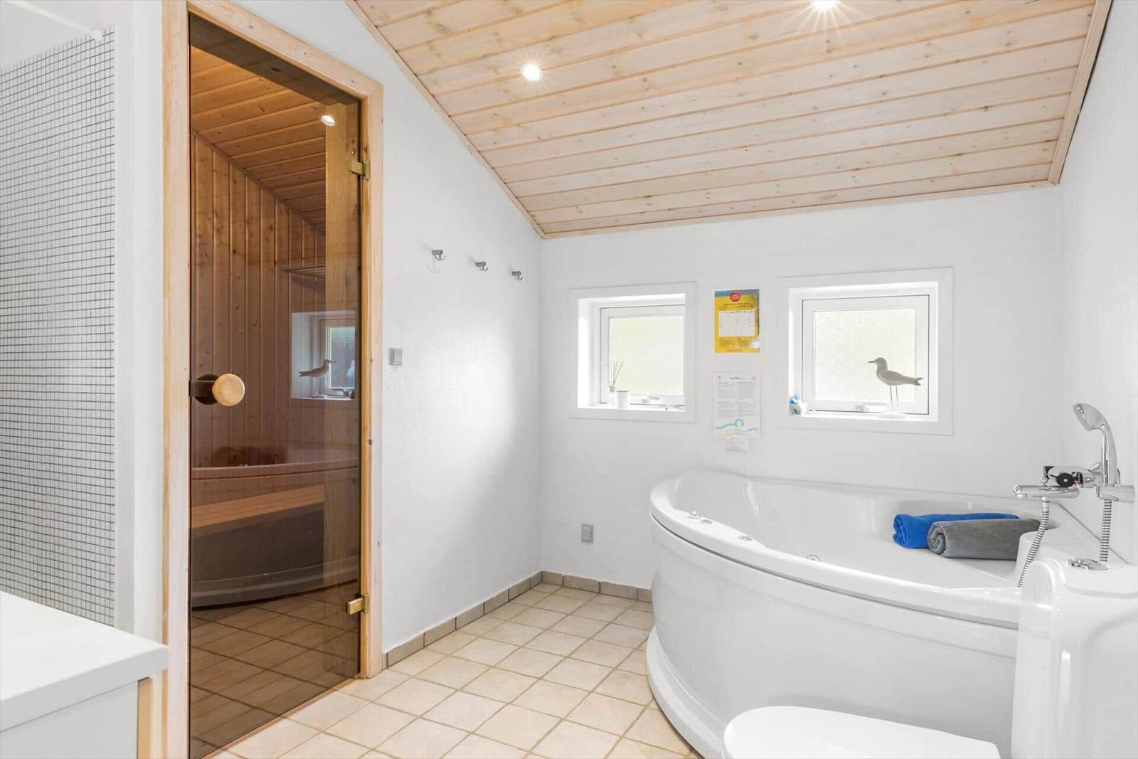 Bath with whirlpool, sauna, and windows with bird decoration.