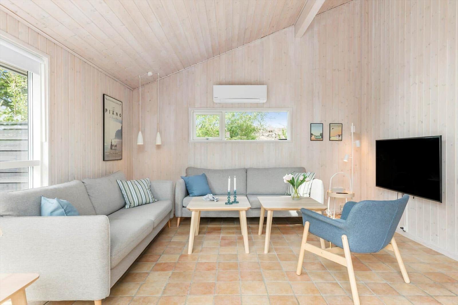 Living room with two sofas, table, chair, and TV mounted on the wall.