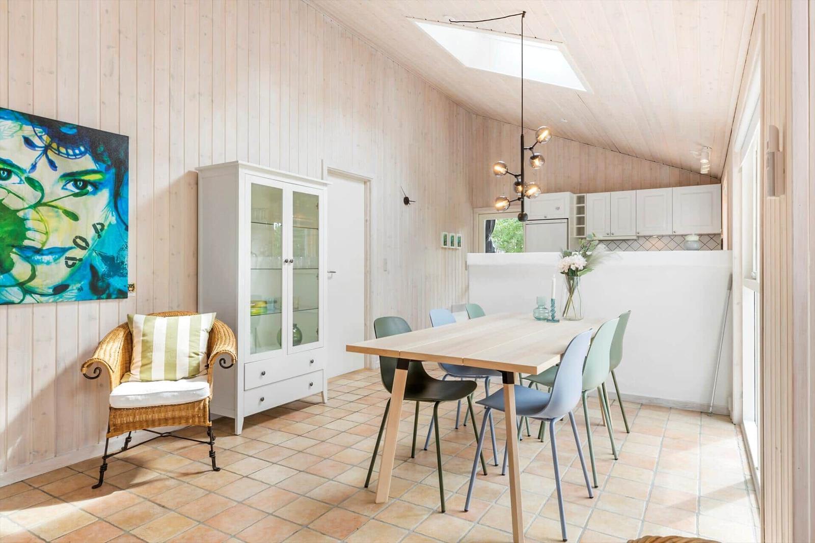 Dining area with table, chairs, and kitchen. Wall art and sideboard are visible.