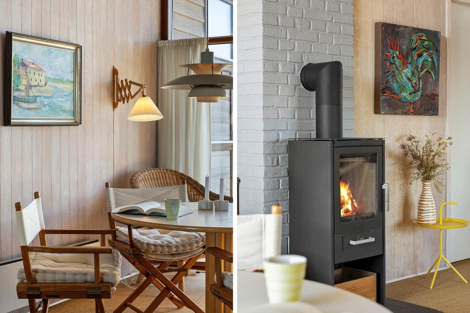 Dining area with wooden chairs and wall art. Fireplace with burning fire and decorative vase.