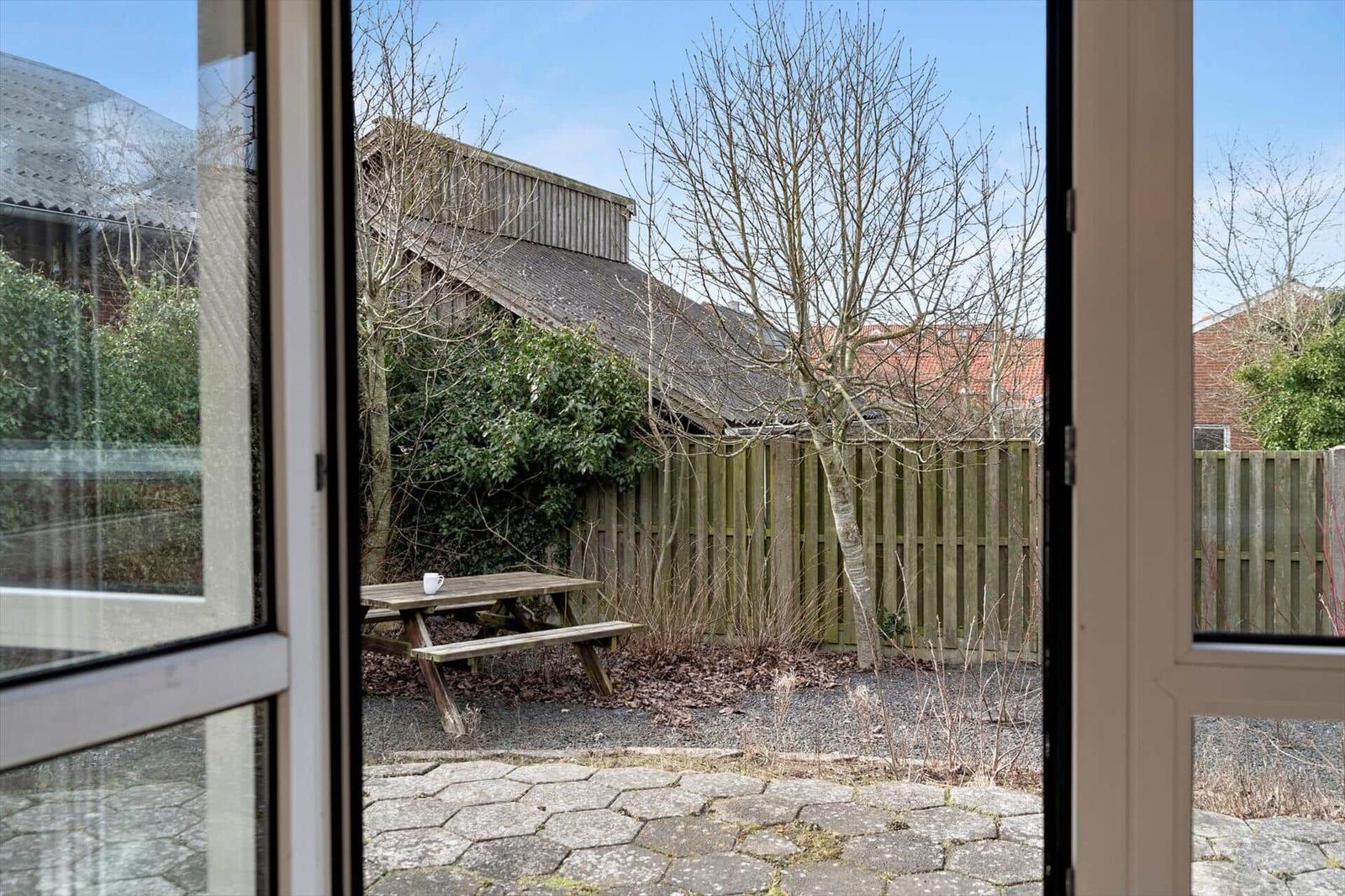 Durch die Tür ist ein Garten mit Holztisch und Zaun zu sehen.