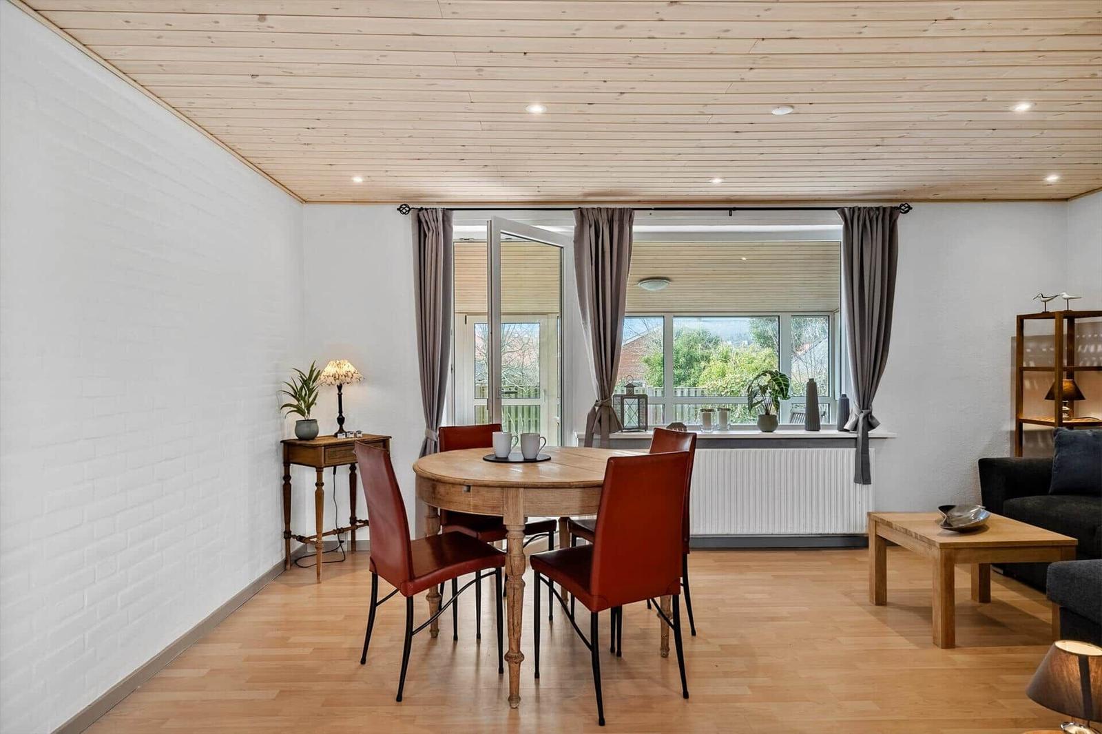 Esszimmer mit Holztisch, roten Stühlen und Fenster zur Terrasse.