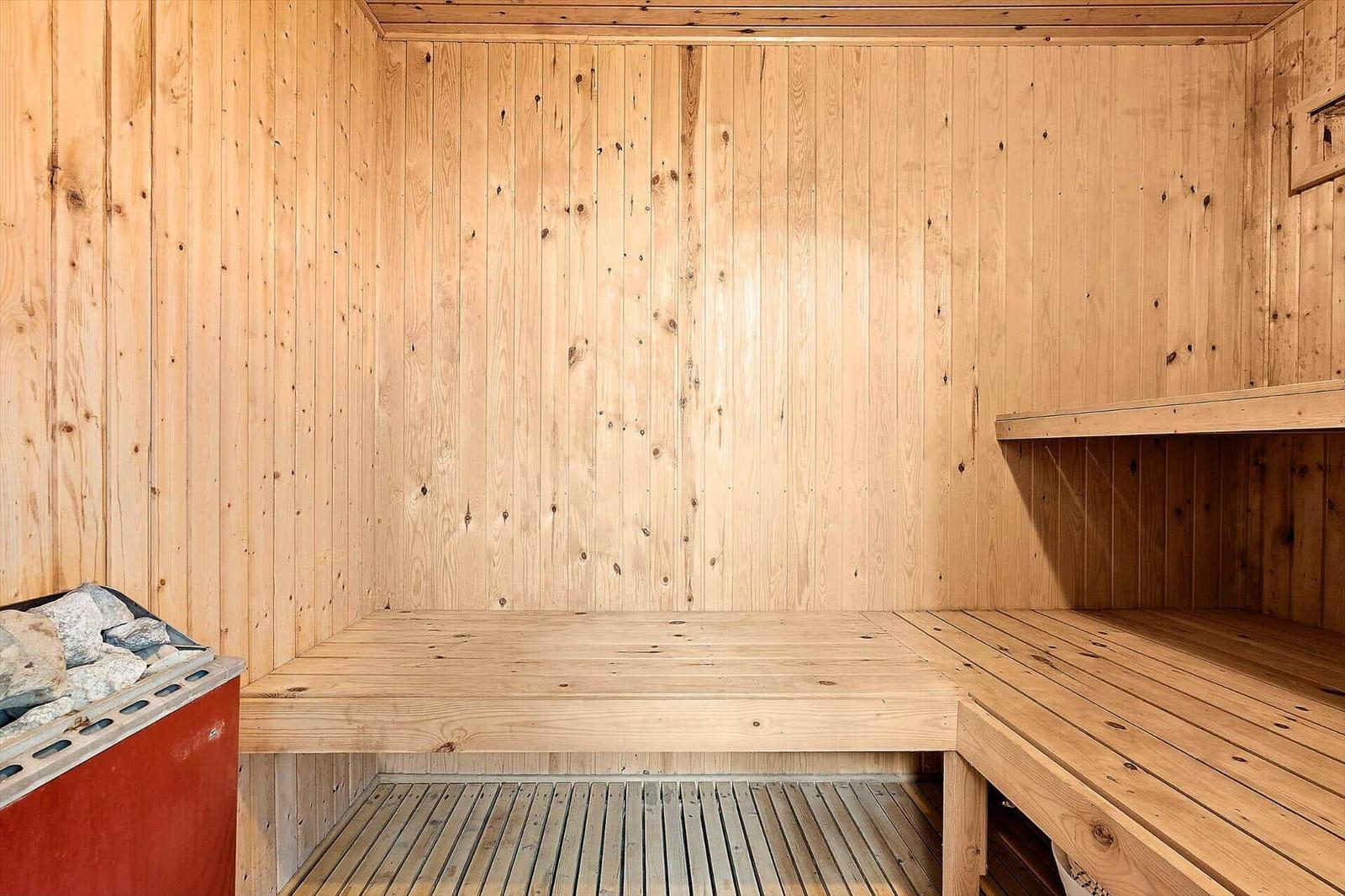 Sauna mit Holzwandverkleidung und mehreren Sitzbänken.