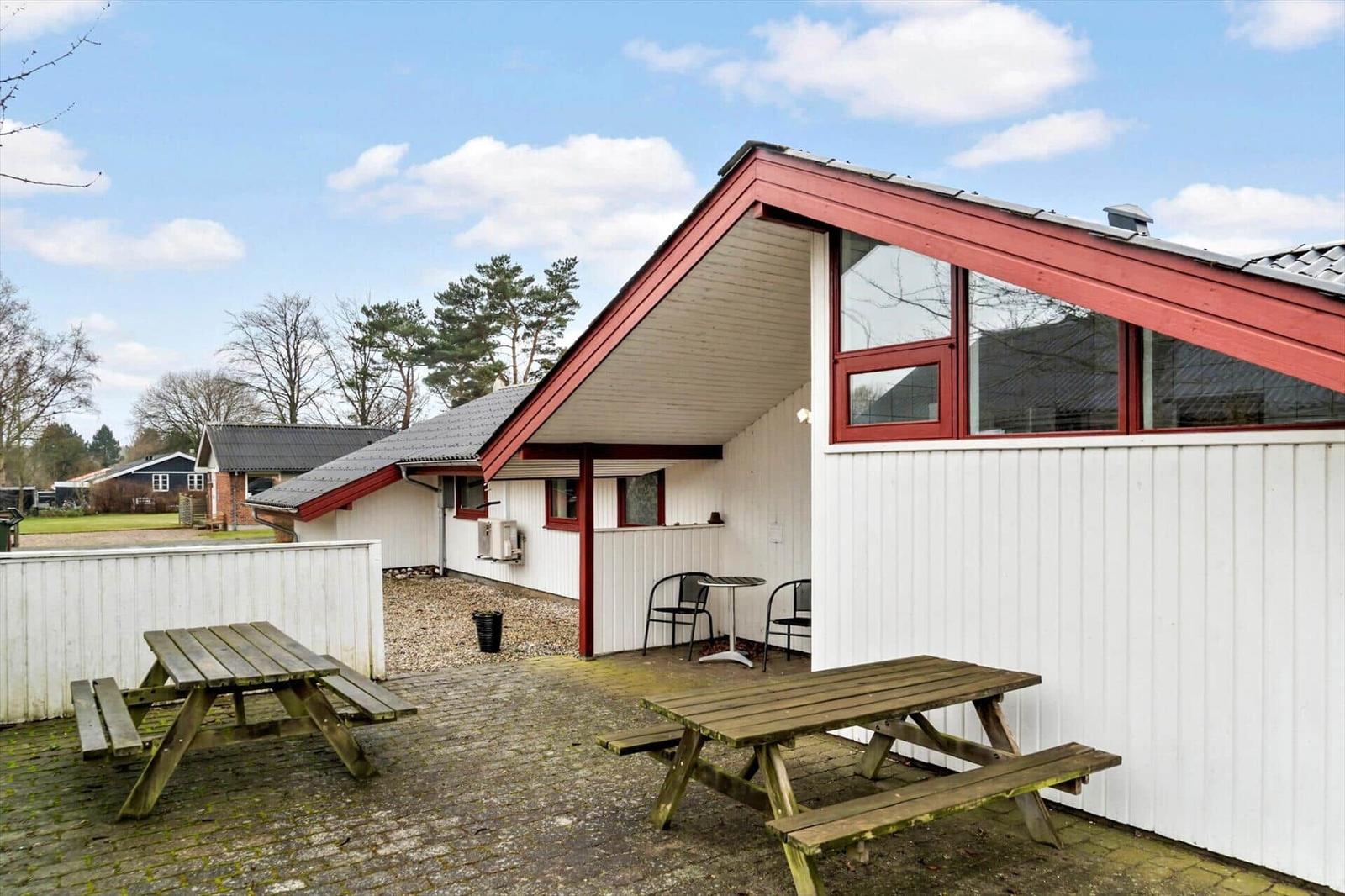Wohnhaus mit Terrasse, Tischen und Stühlen im Freien.