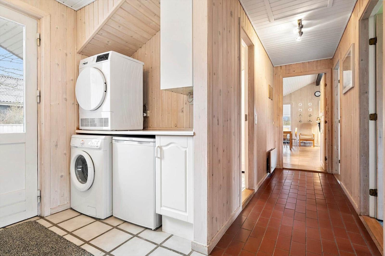 Wäscherei mit Waschmaschine und Trockner. Flur mit Holzwänden und Terrakottboden.