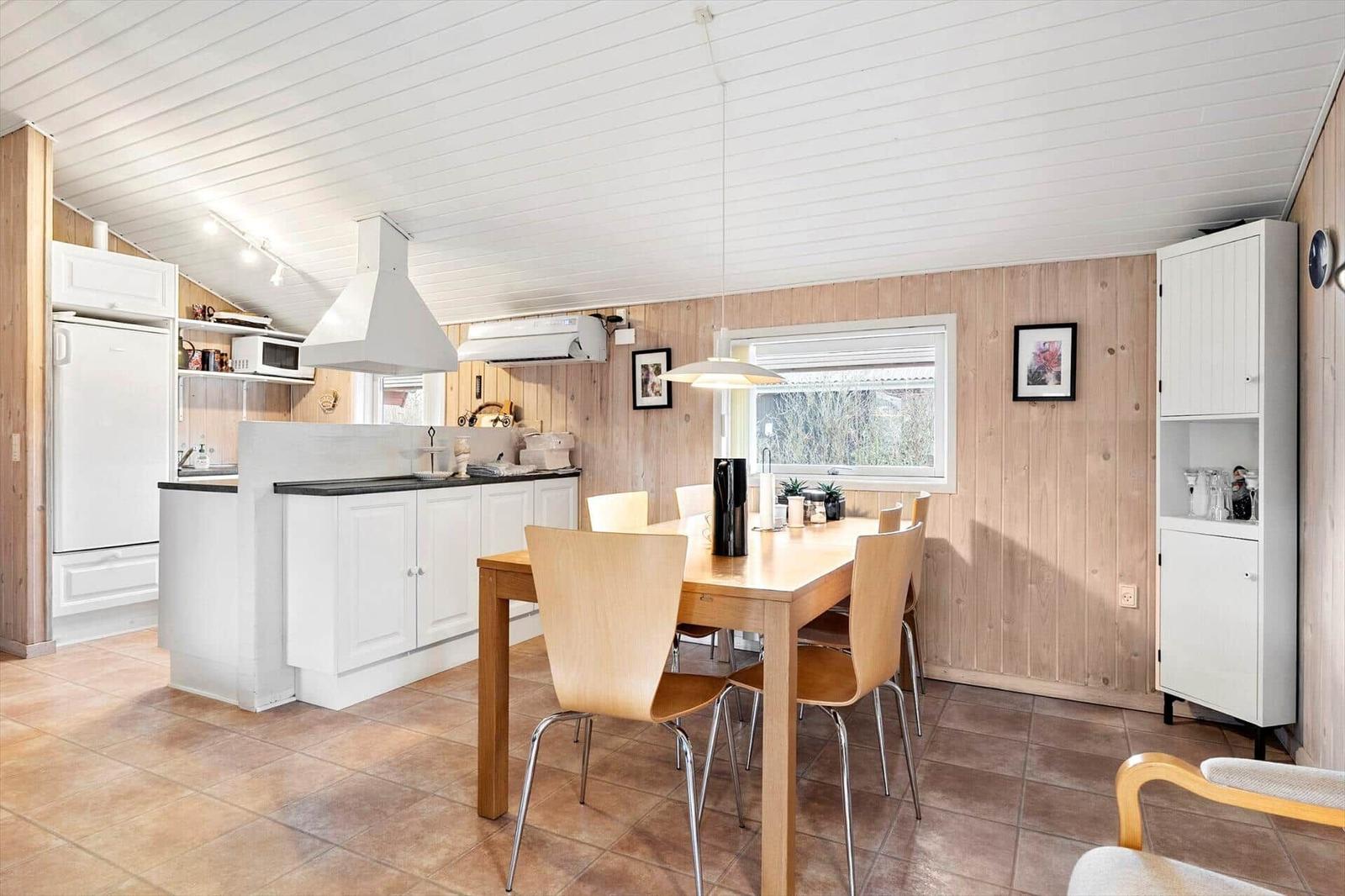 Küche mit Essbereich, Holzwand und Esszimmertisch mit Stühlen.