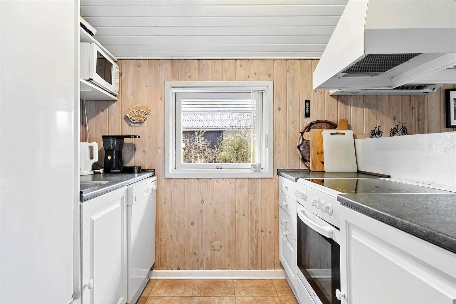 Küche mit weißen Schränken, Holzwand und Fenster