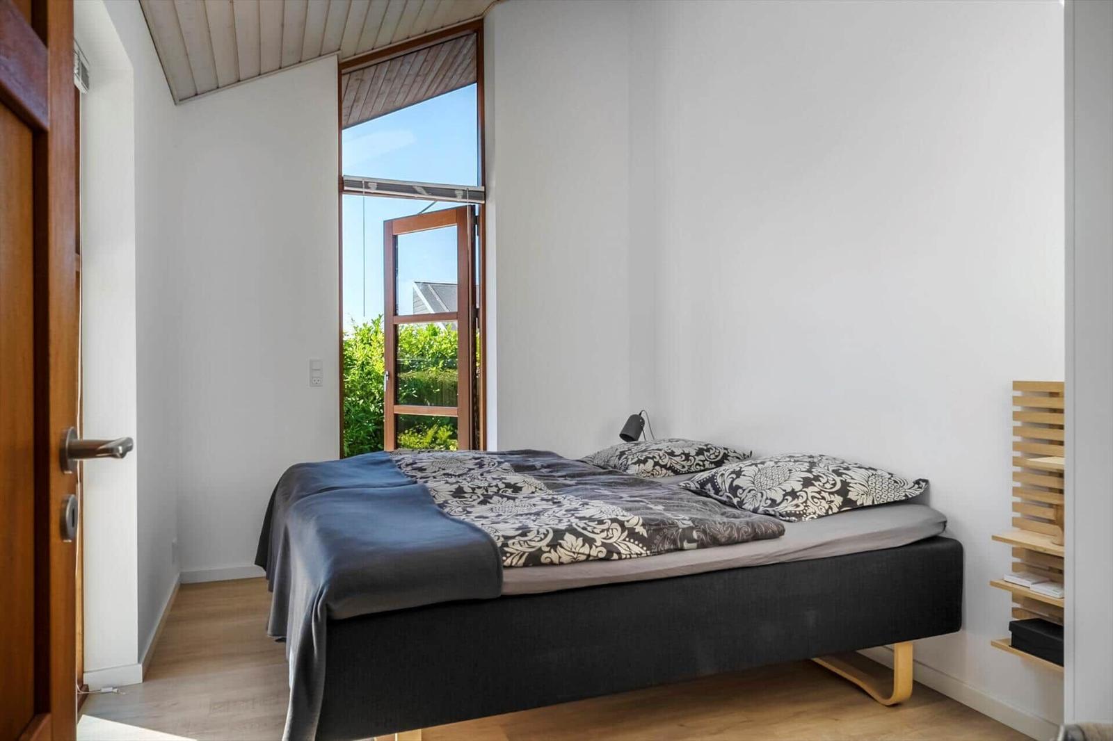 Schlafzimmer mit Bett, Fenster und Holzregal