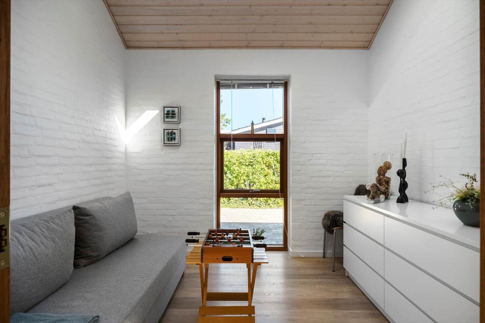 Wohnzimmer mit Sofa, Tischfußball und Fenster zum Garten