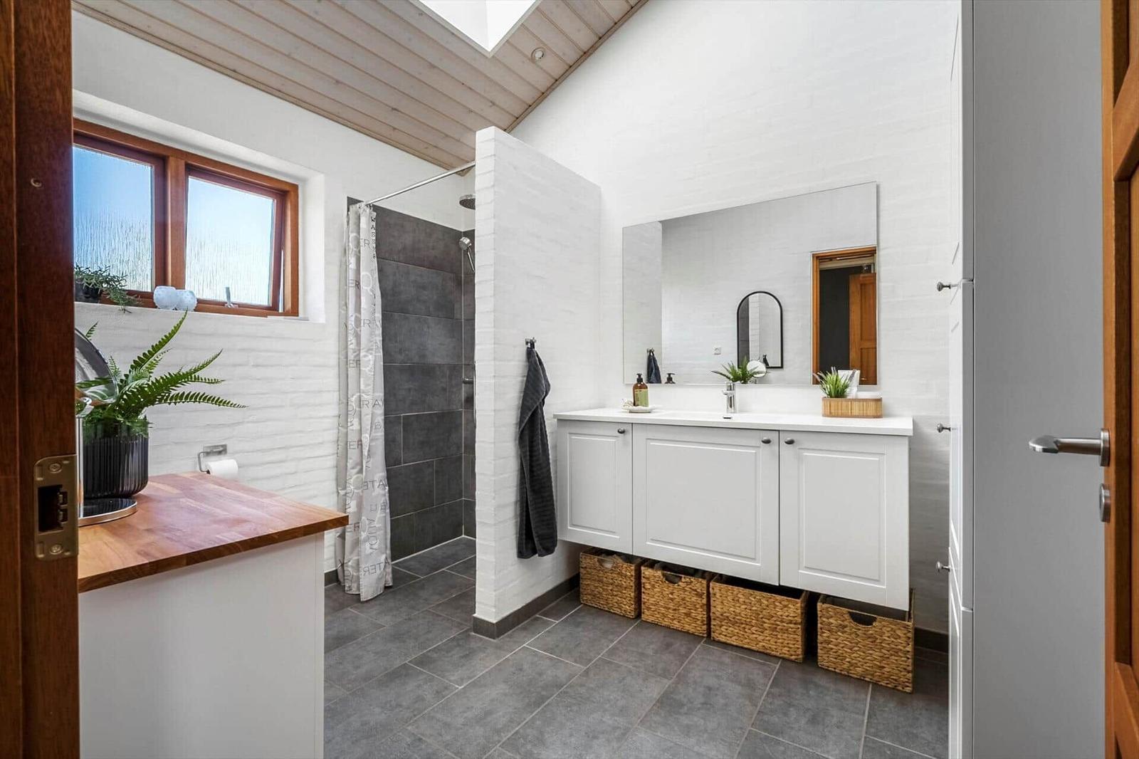 Badezimmer mit Dusche, Waschbecken und Fenster