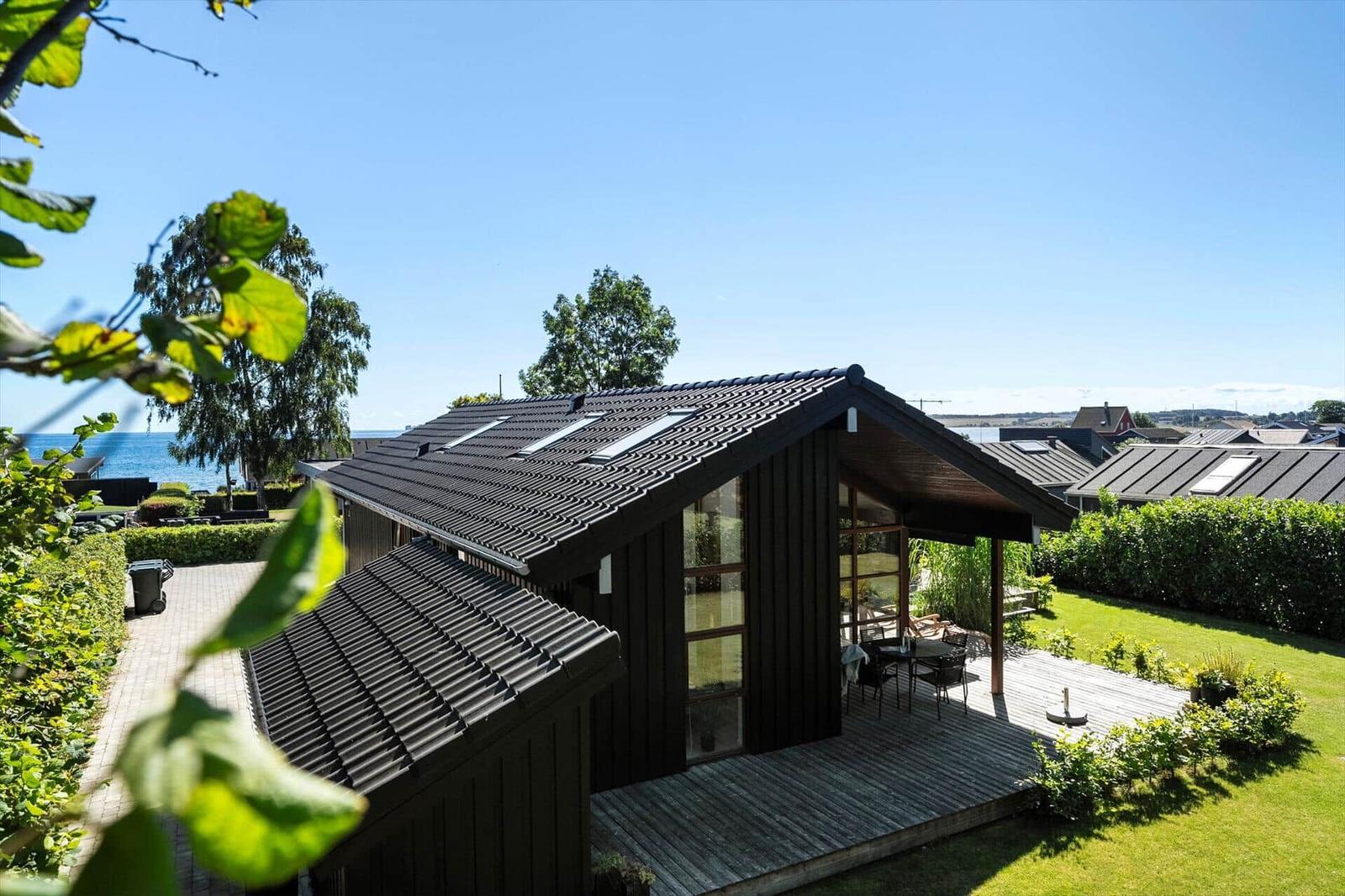 Moderne Holzhütte mit Terrasse, Garten und Meerblick.