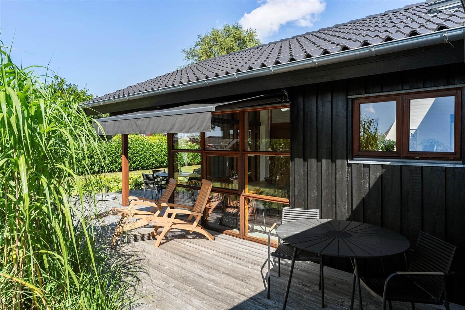 Terrasse mit Sitzgelegenheiten und Blick auf Garten und Haus.