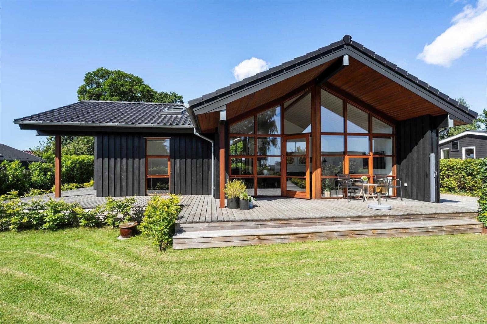 Moderne Holzhütte mit großem Glasbereich und Terrasse im Garten.