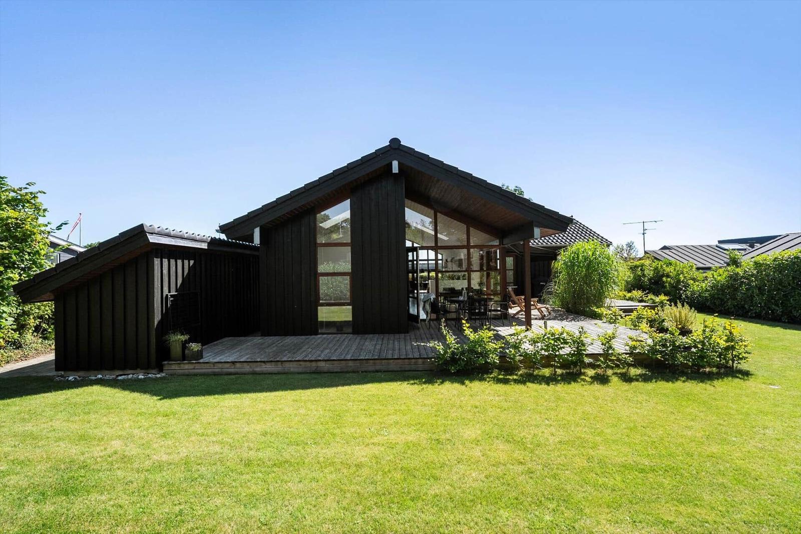 Moderne Holzhütte mit großem Garten und Terrasse. Durchgehendes Glas ermöglicht viel Tageslicht.