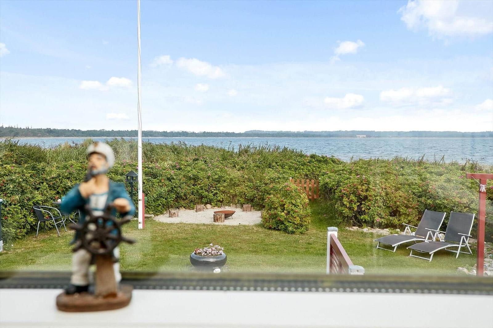 Villa mit Blick aufs Wasser, Garten mit Liegestühlen und Steg.