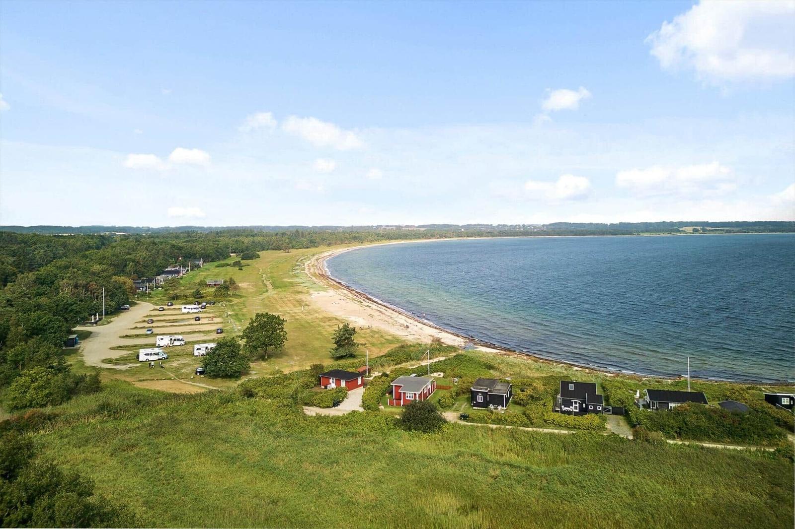 Strandnahe Ferienhäuser mit Campingplatz und grüner Landschaft.