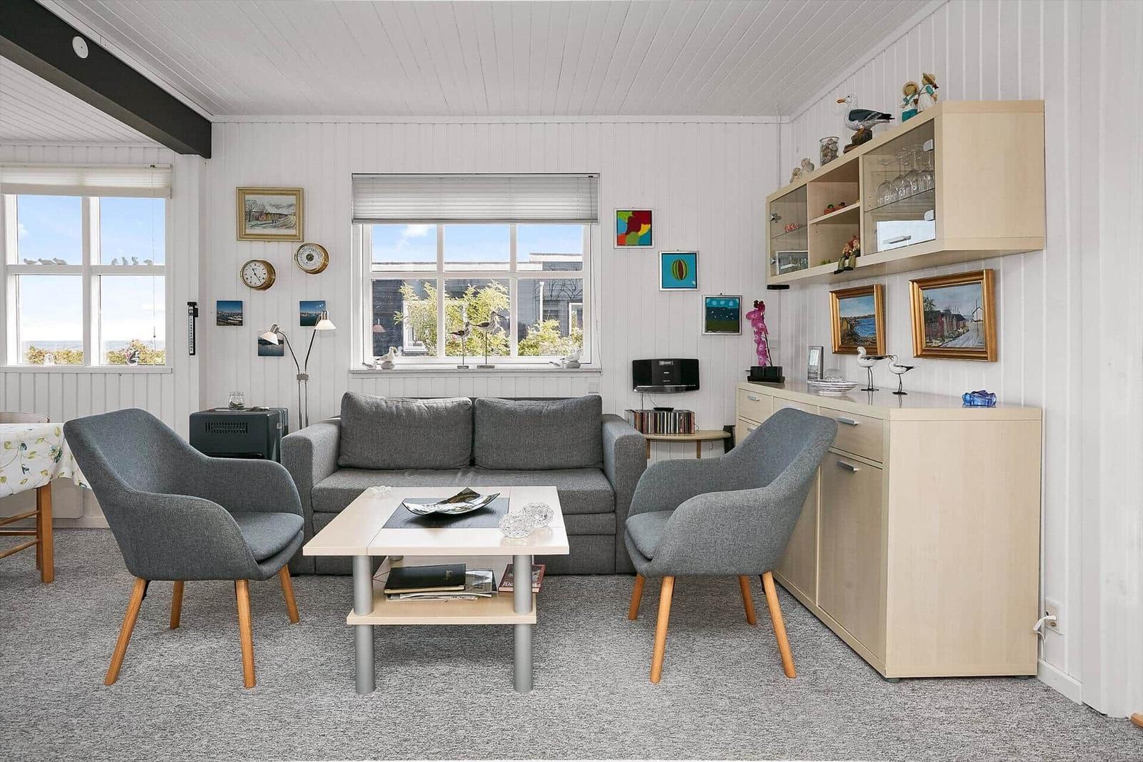 Wohnzimmer mit Sofa, zwei Sesseln und Küchenzeile.