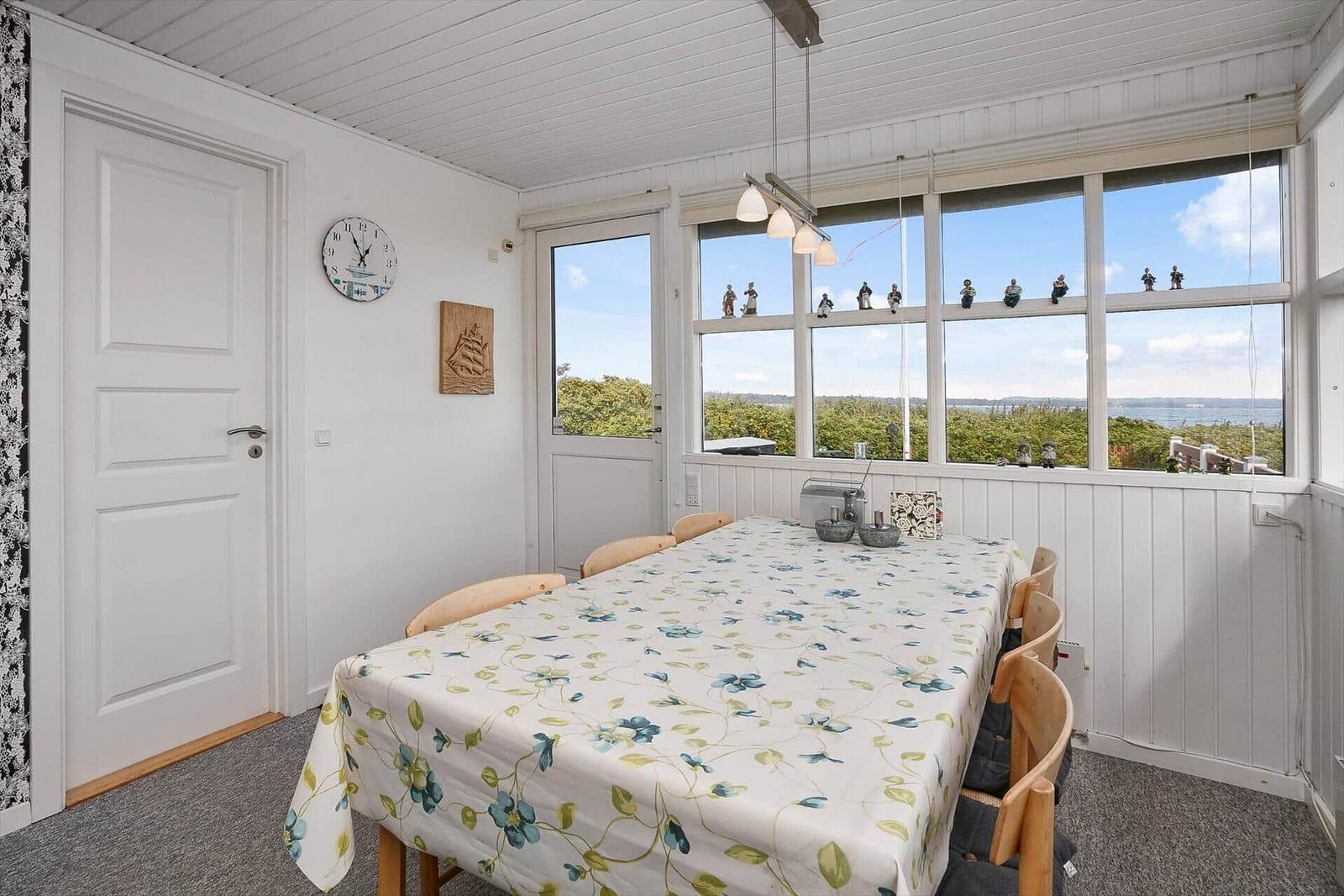 Esszimmer mit Tisch, Stühlen und Blick aufs Wasser.