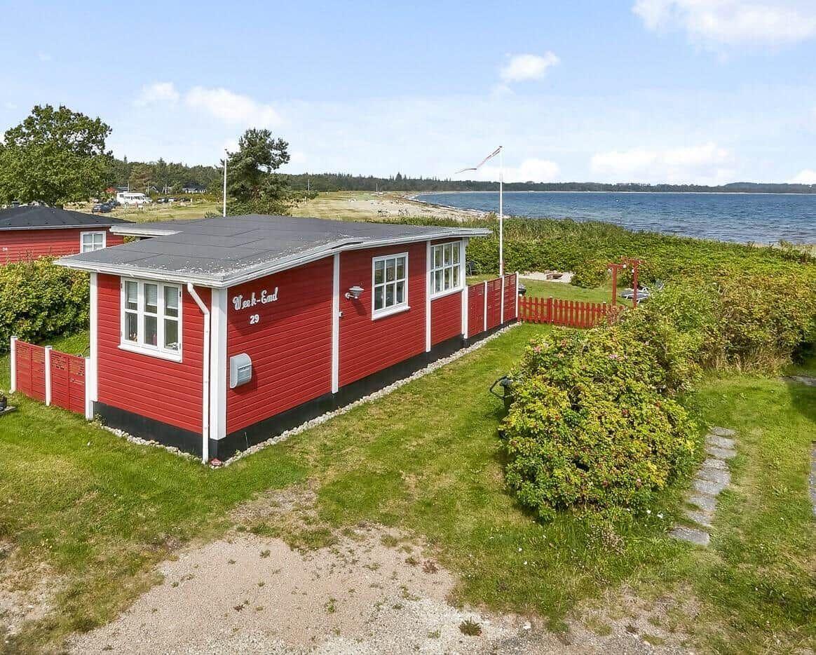 Rotes Strandhaus mit Garten und Blick aufs Wasser.
