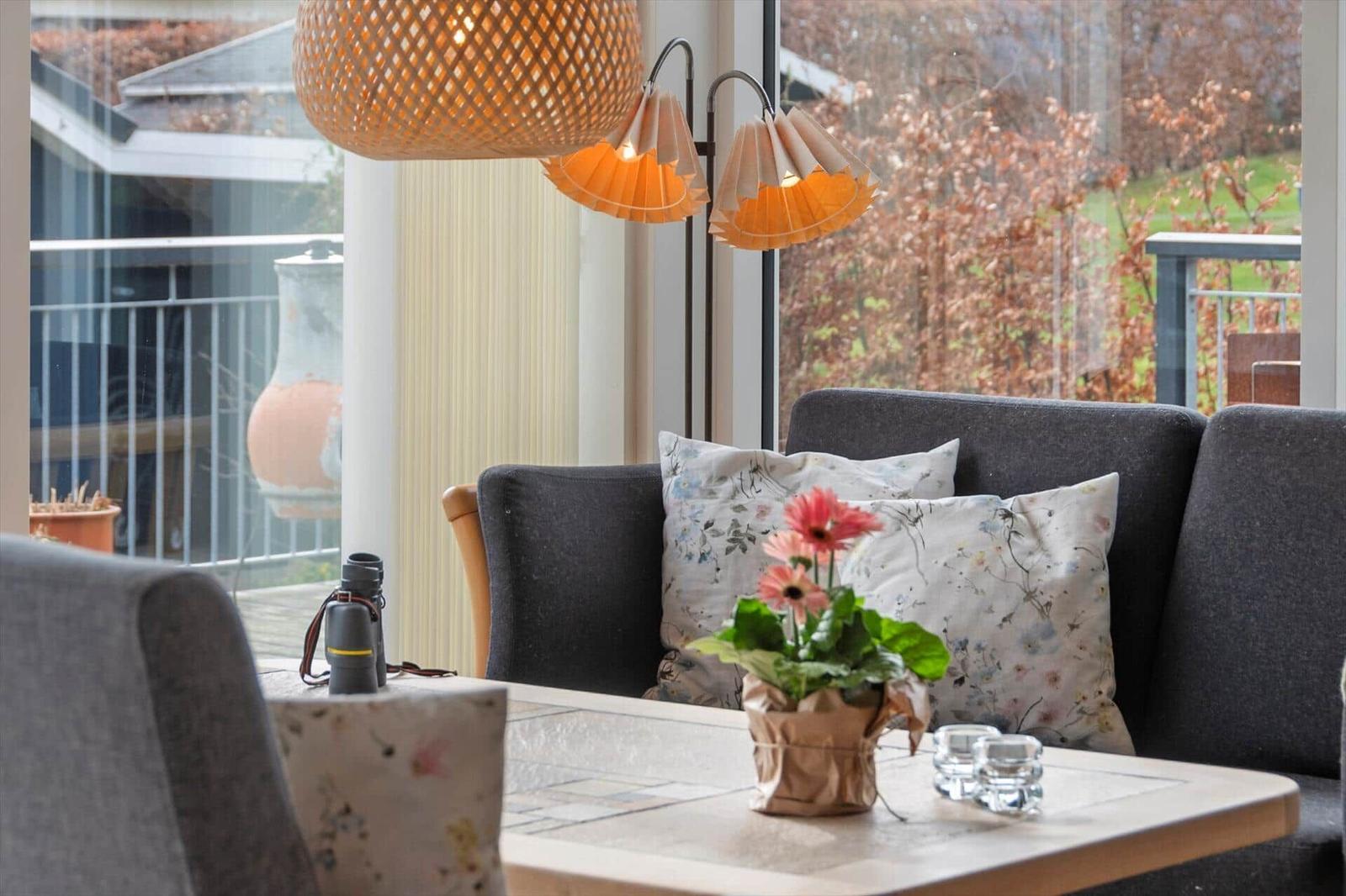 Ein Wohnzimmer mit grauem Sofa, Tisch und Fensterblick.