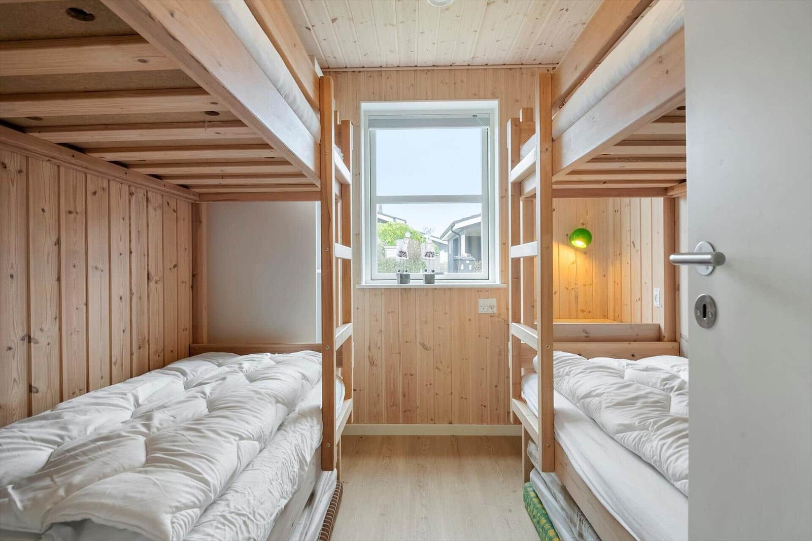 Zimmer mit zwei Etagenbetten, Holzwand und Fenster.