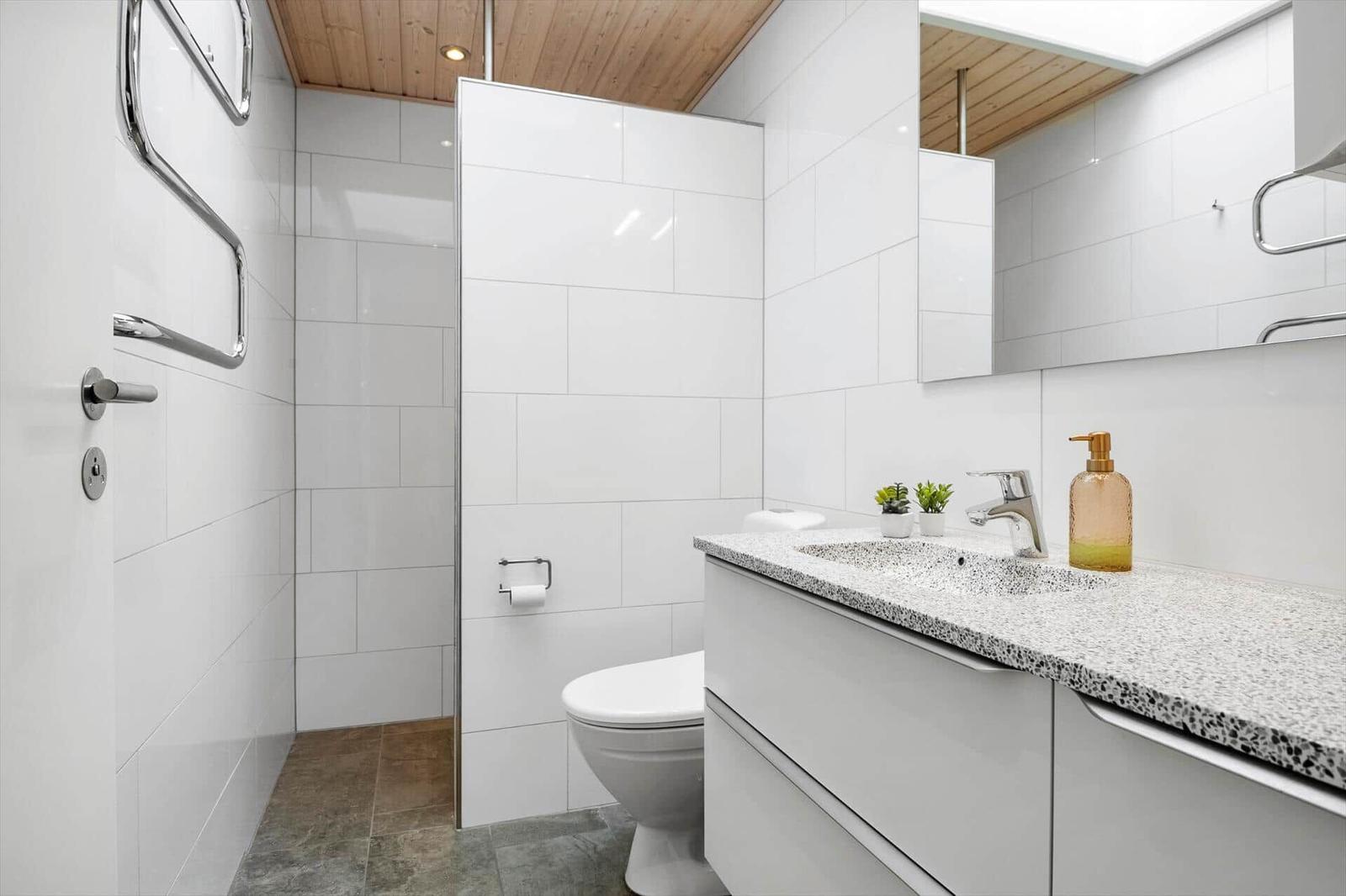 Badezimmer mit Dusche, Toilette und Waschbecken mit Spiegel.