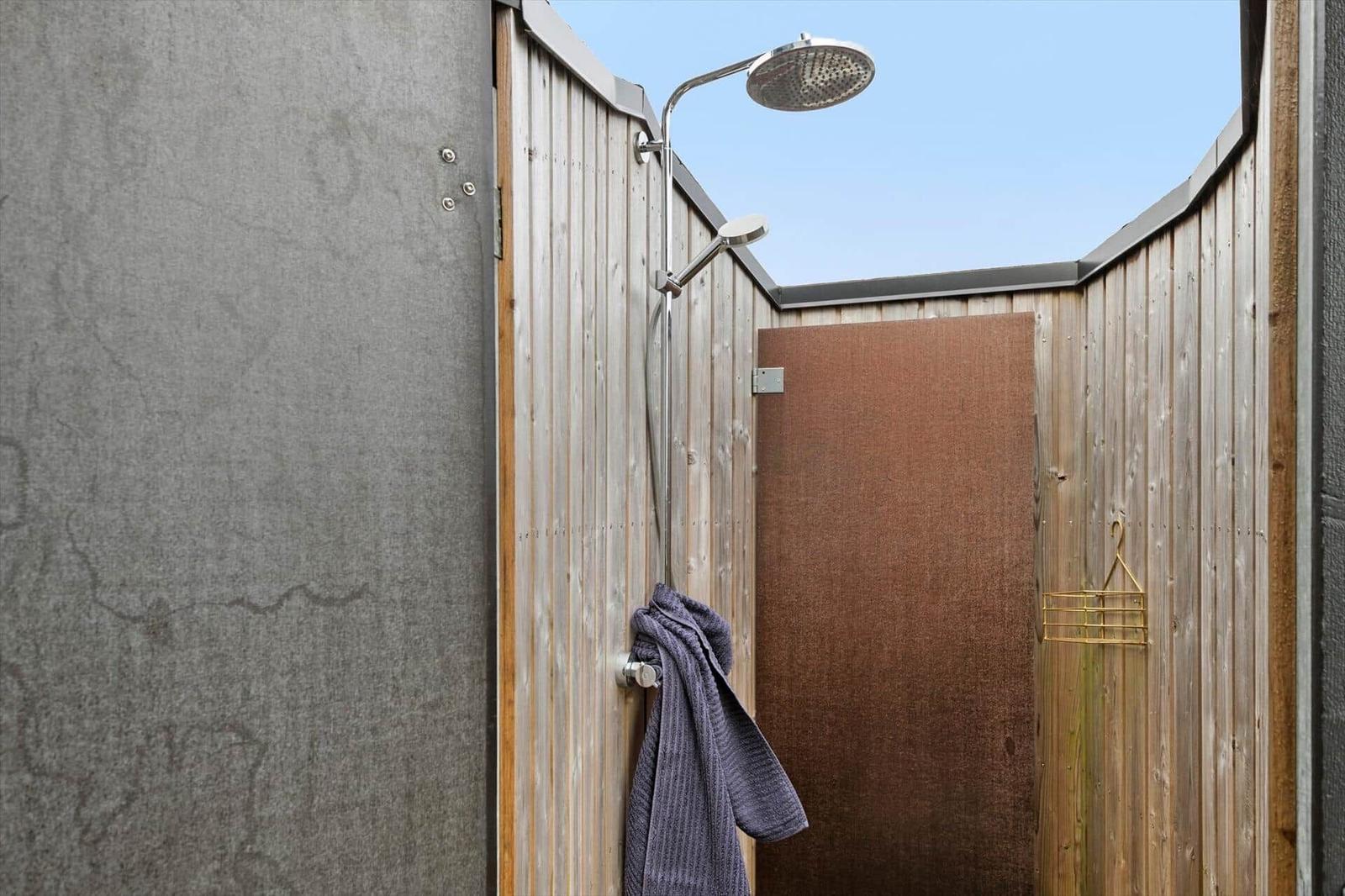 Außen-Dusche mit Duschbrause und Handtuch an Wand
