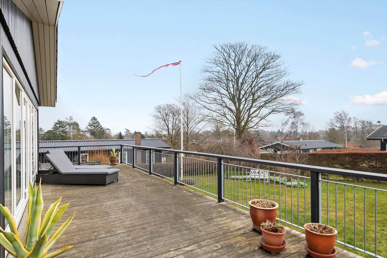 Terrasse mit Liege, Flagge und Blick auf Grünflächen
