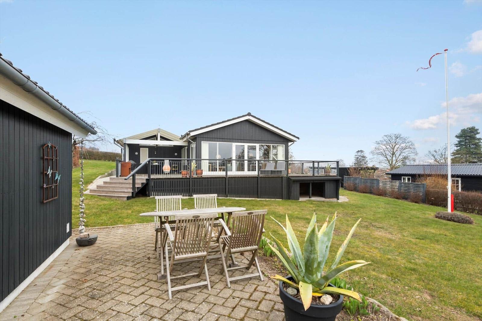 Haus mit Terrasse und Gartenbereich mit Tisch und Stühlen.