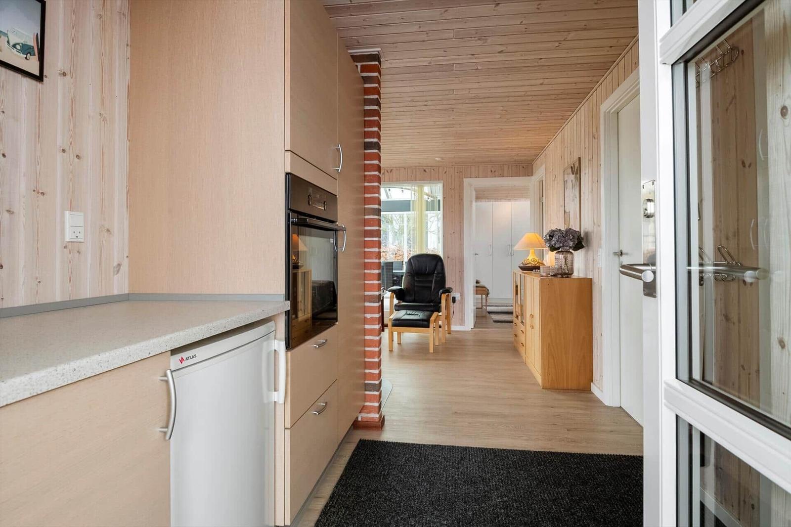 Küche mit Einbauküche und Blick in Wohnbereich mit Sessel.
