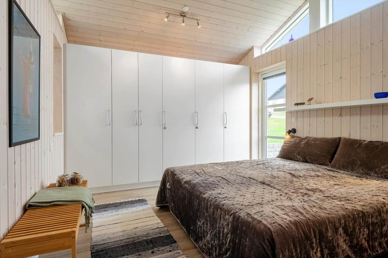 Schlafzimmer mit Bett, Kleiderschrank und Fenster.