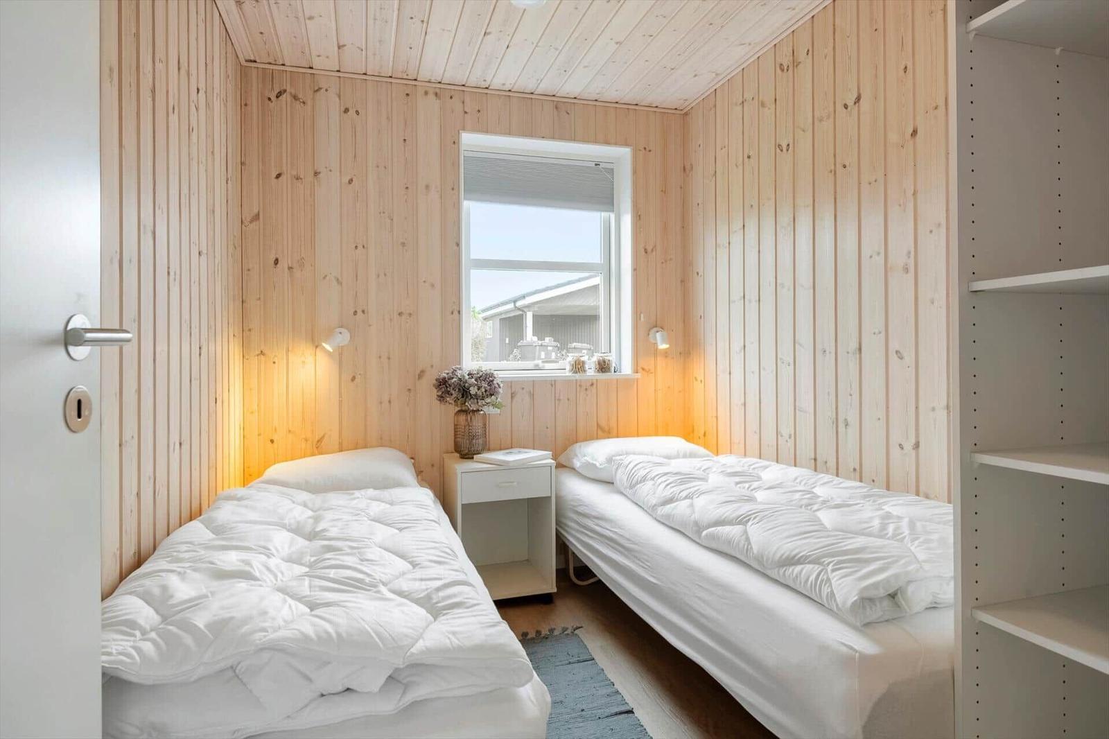 Zwei Betten in einem Zimmer mit Holzwänden und einem Fenster.