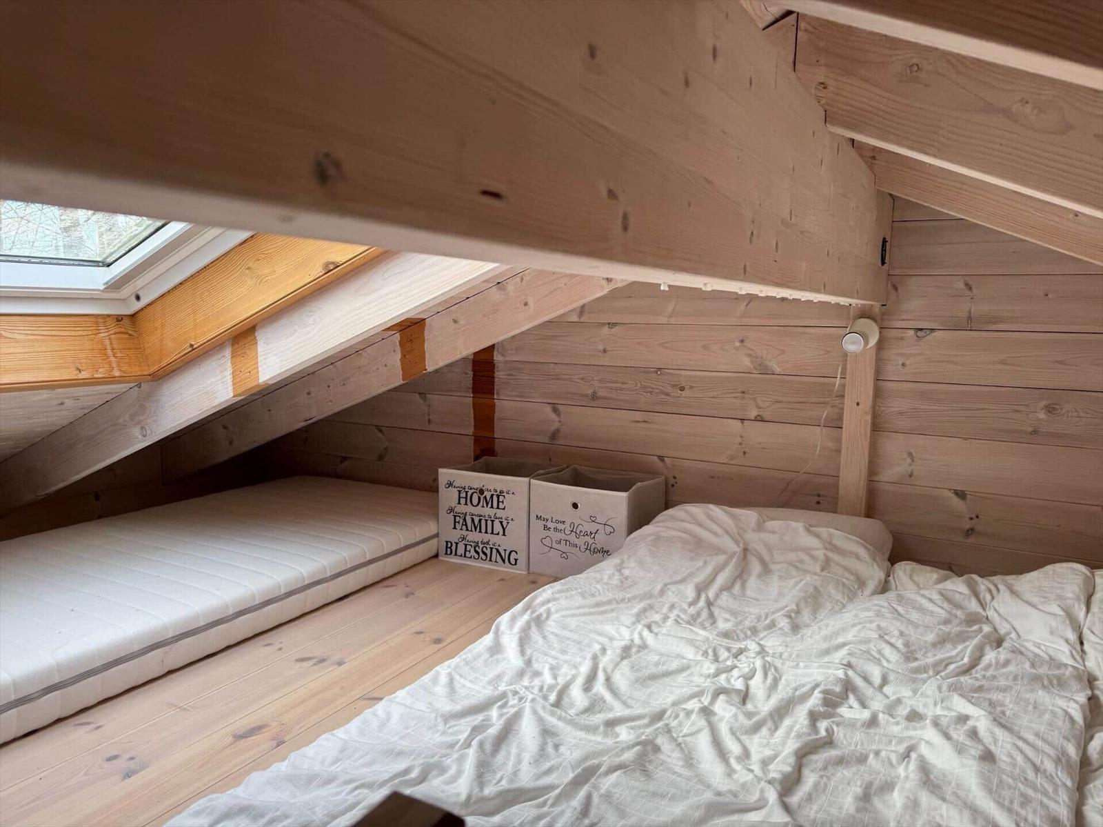 Dachgeschosszimmer mit Matratze, Bett und Fenster.