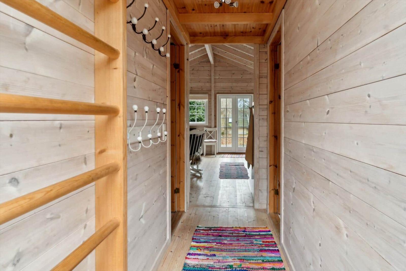 Flur mit Holzwand und buntem Teppich führt in Wohnbereich.