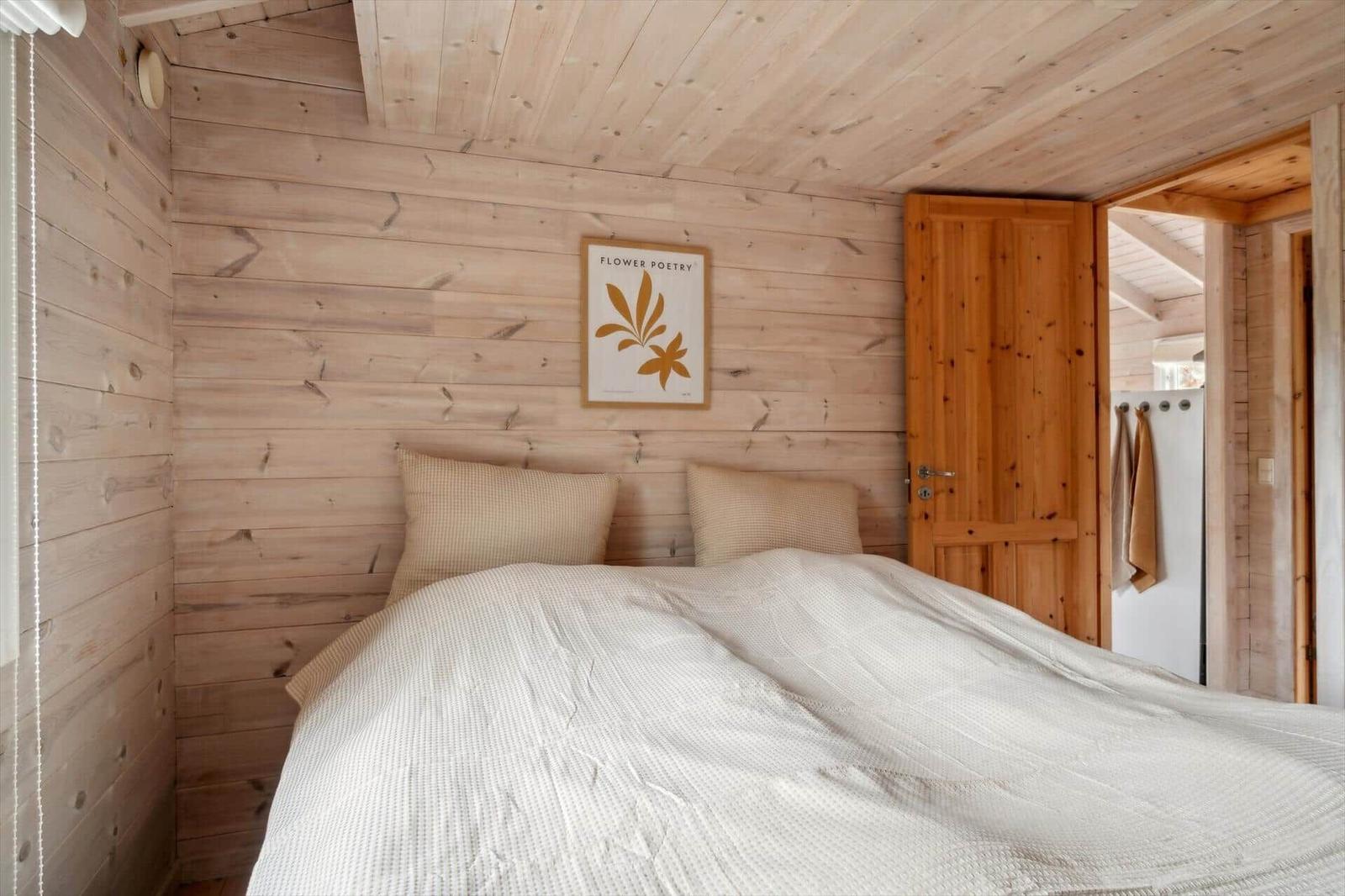 Schlafzimmer mit Holzwand, Bett und Bild an der Wand.