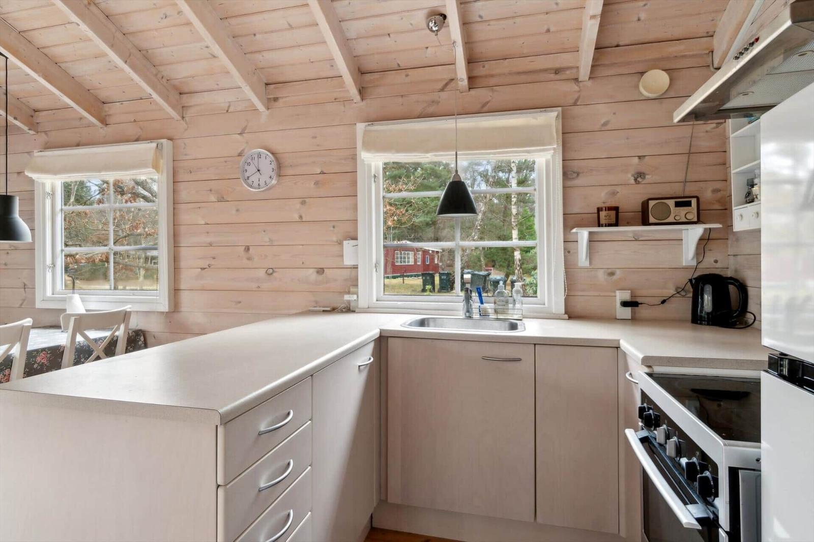 Küche mit Holzwänden, Arbeitsplatte und Fenster.