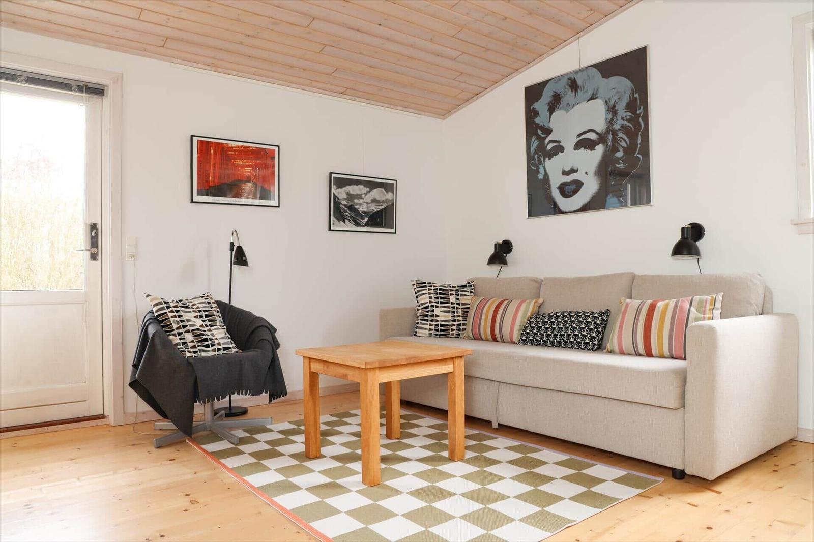 Wohnzimmer mit Sofa, Tisch, Teppich und Wandbildern.