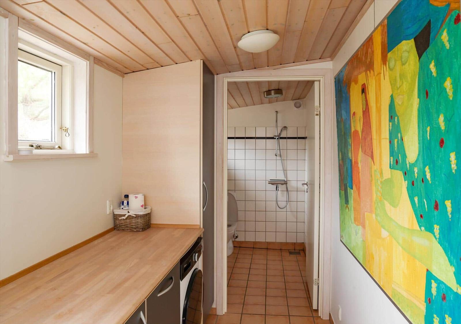 Badezimmer mit Dusche und Waschmaschine. Wandbild und Holzdecke.