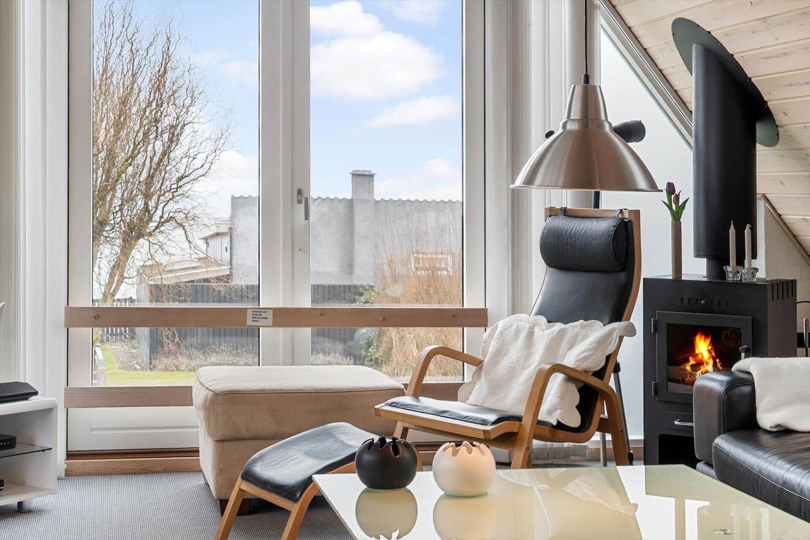 Ein Wohnzimmer mit Sessel, Kamin und großem Fenster. 