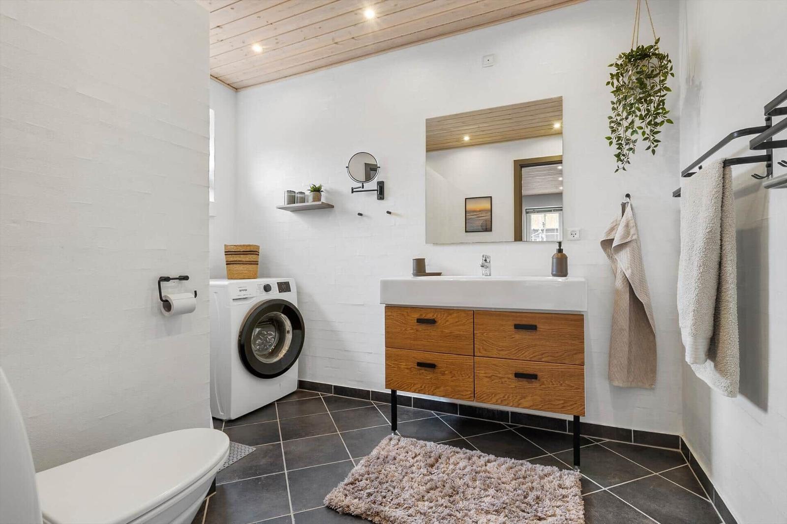 Badezimmer mit Waschmaschine, Waschtisch und Spiegel