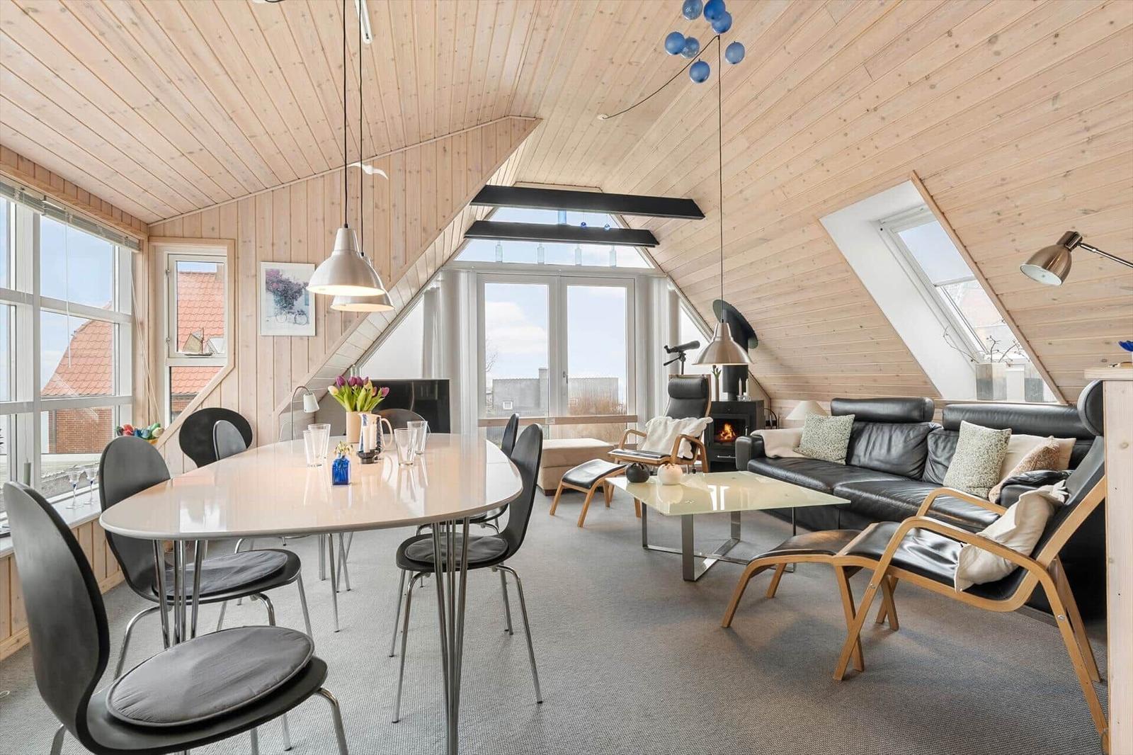 Wohn- und Essbereich mit Holzdecke, Sofa, Tisch und Stühle.