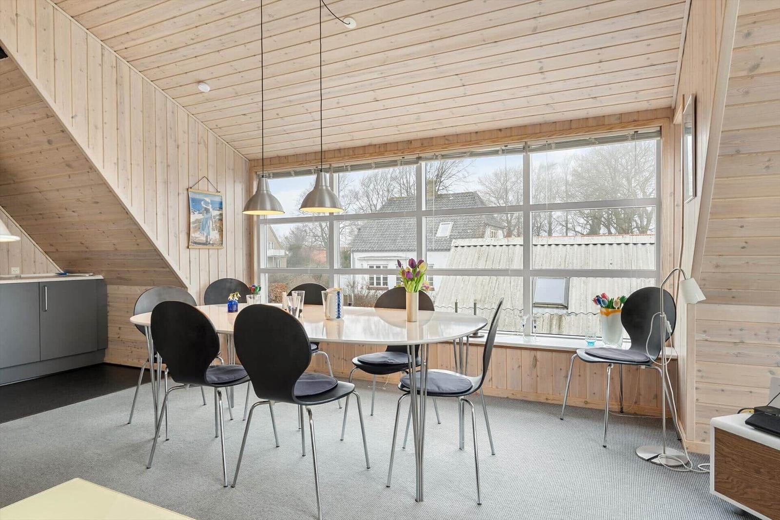 Esszimmer mit runden Tisch, schwarzen Stühlen und großem Fenster.