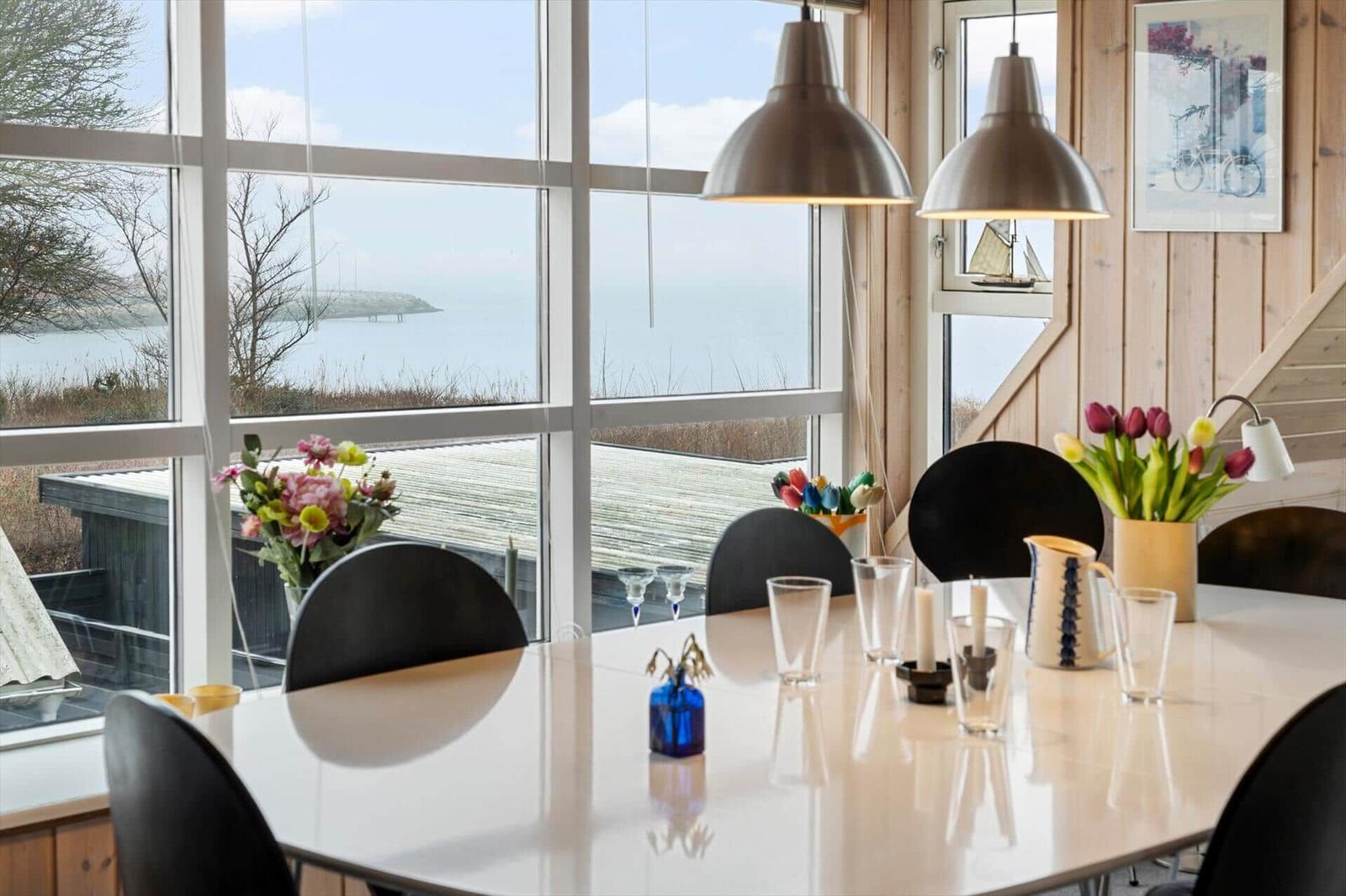 Esszimmer mit Blick aufs Meer und Blumenarrangement.
