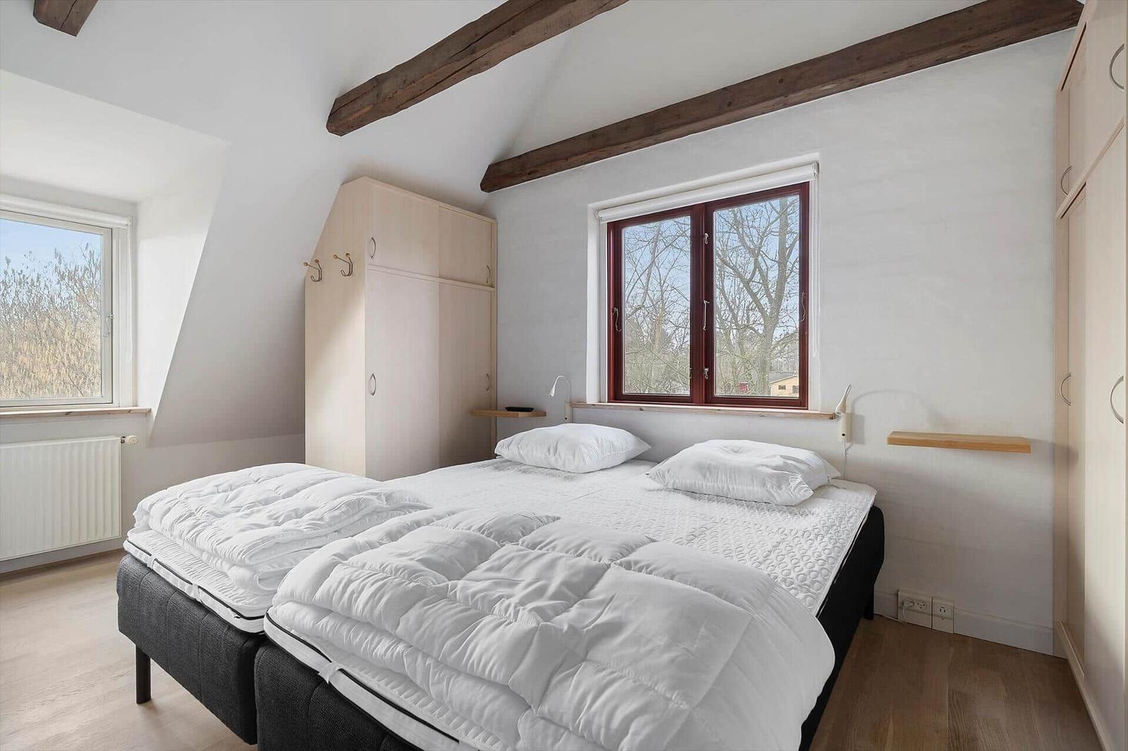 Schlafzimmer mit Doppelbett, Holzbalken und Fenstern