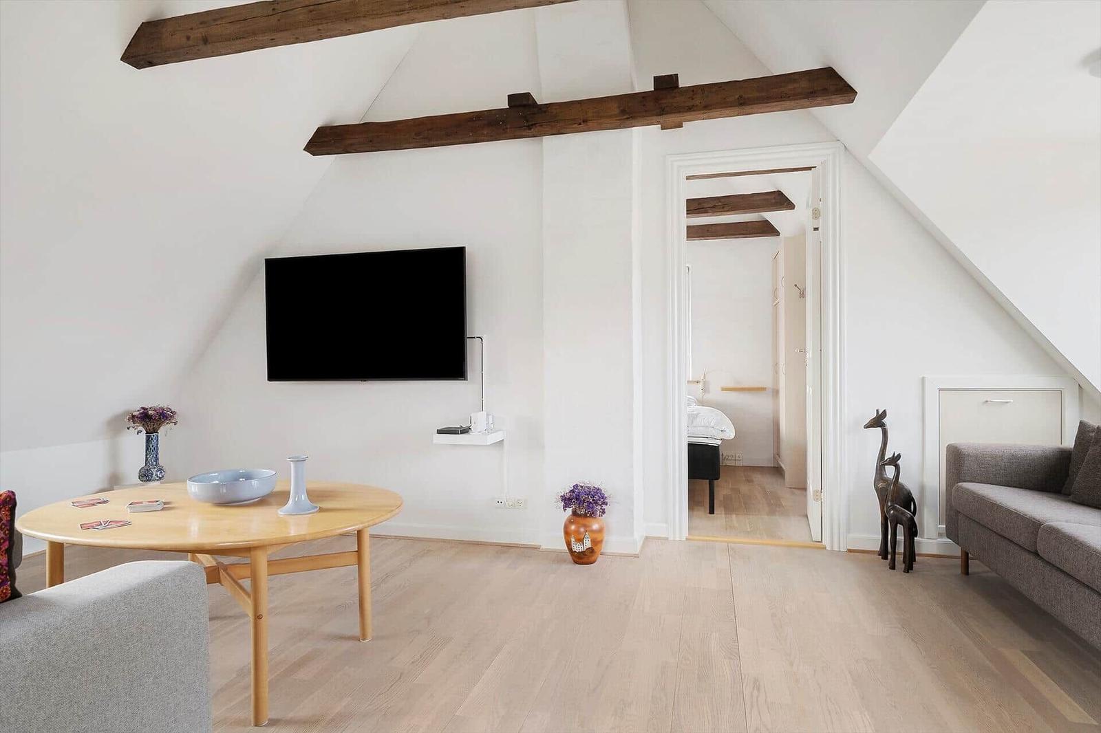 Wohnzimmer mit TV, Couch und Tisch unter Holzbalken