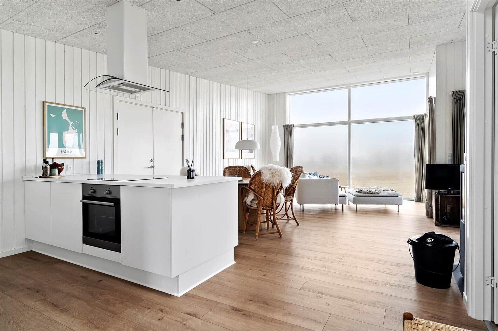Küche mit Insel, Essbereich und Wohnzimmer mit großem Fenster.