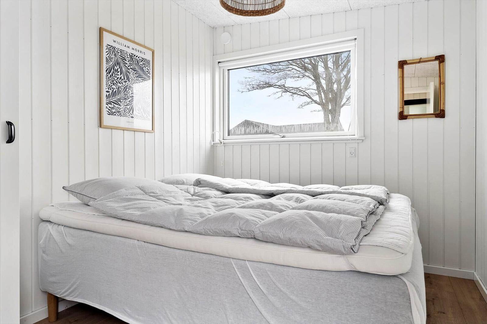 Schlafzimmer mit Bett, Fenster und Wanddekoration.