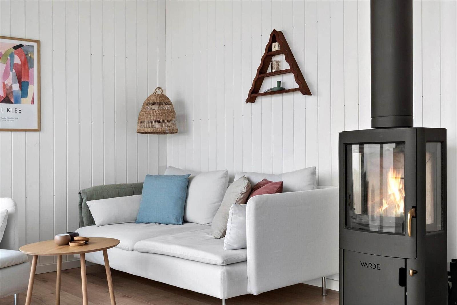 Wohnzimmer mit Sofa, Kamin und Wandregal.